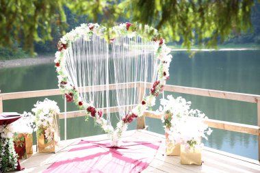 Dağlarda, ormanlarda ve düğün günlerinde bir gölün yakınındaki tahta bir teknede çiçeklerle dolu bir kalp.