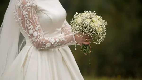 Gelin dağlarda bir buket tutuyor.