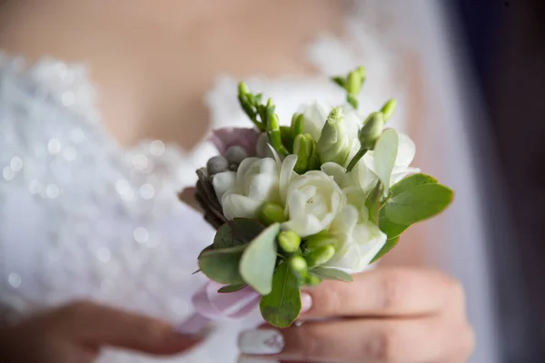Gelin bir buket gül ve düğün tutuyor.