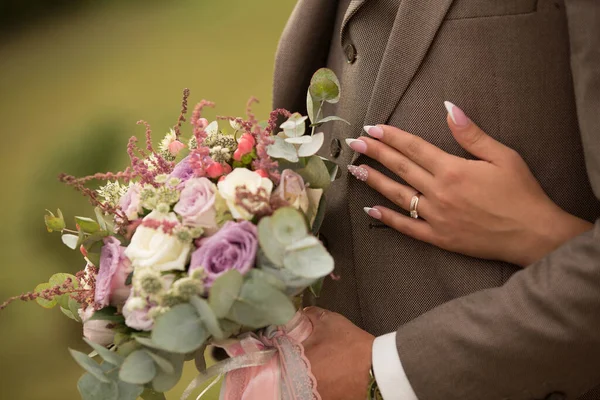 Gelinin eli damadın ceketinde bir buket çiçek ve düğün ile