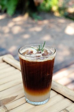 Yakın plan buzlu americano bambu masasında.