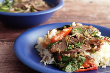 Yakın plan baharatlı fesleğen, ahşap masada sığır eti ve kızarmış pirinç.