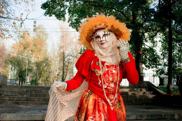 少女在西装 在狂欢节面具在秋天树的背景 — 图库照片