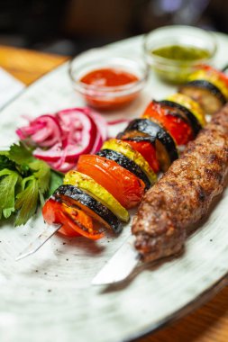 Kuzu kebabı ve ızgara sebzeler yakın planda.