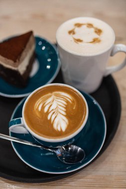 Bir fincan kapuçino ve masanın üzerinde bir parça kek. Üst görünüm