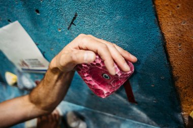 Kapalı alanda tırmanma eğitimi. Kapalı alan duvarına tırmanan adam. Parmaklarına odaklan.