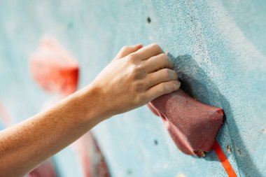 Kapalı alanda tırmanma eğitimi. Kapalı alan duvarına tırmanan adam. Parmaklarına odaklan.