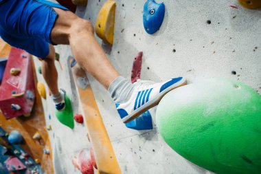 Kapalı alan tırmanma duvarı. Erkek ayağının tırmanma duvarındaki yakın plan görüntüsü