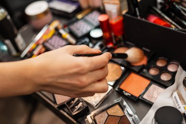 Makyaj sanatçısı güzellik salonunda çalışıyor. Makyaj için makyaj malzemeleri. Makyaj sanatçısı makyaj yapar. Ellerin ve kozmetik ürünlerin yakın çekimi