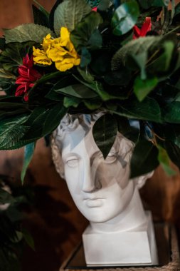 Beyaz alçı başlık bir çiçek çelengiyle süslenmiş. Antika kafa.