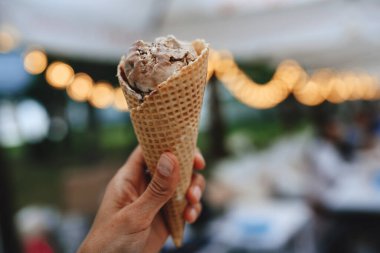 Kız elinde çikolatalı dondurma tutuyor, yakın plan. Kırpılmış resim, cansız