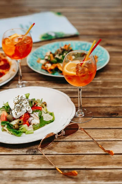 Table with food and drinks on the restaurant terrace on a summer day. Aperol spritz in a summer