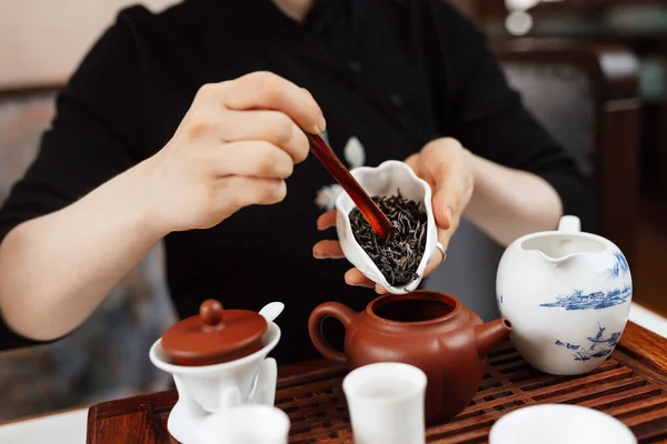 Chinese tea ceremony. Girl pours tea leaf into a teapot