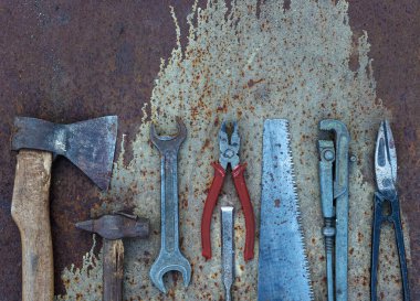 Eski inşaat aletleri: çekiç, testere, kerpeten, vs. Paslı metalin düz arka planında yatıyordu.