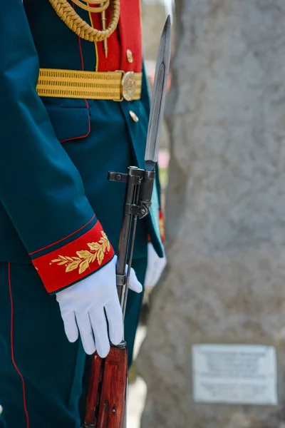 The guard of honor officer in white gloves holds a weapon. Close-up of hands. Victory Day in Russia