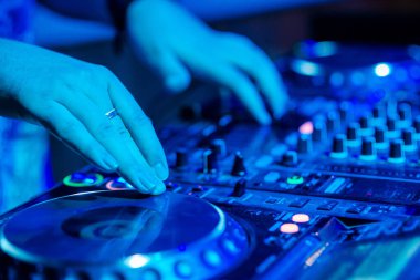 Bir gece kulübünde DJ şarkı karıştırıyor. Yakın plan el.