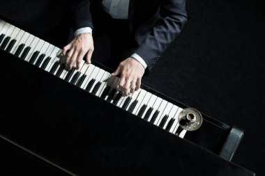 Bir adam piyano çalıyor, elleri yakın, yukarıdan aşağı. Konser piyanisti.