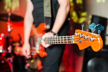 Müzisyen sahnede elektro bas gitar çalar. Gitar boynu, bir müzisyenin elinde rock müzik konseri için yakın çekim. Parmaklarını panoya koy. Gitar boynu, bir müzisyenin elinde rock müzik konseri için yakın çekim. Parmaklar panoda.