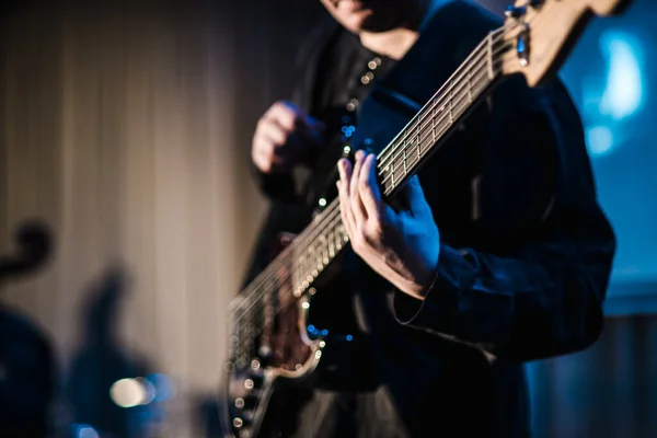 Müzisyen sahnede elektro gitar çalar. Gitar boynu, bir müzisyenin elinde rock müzik konseri için yakın çekim. Parmaklar panoda.