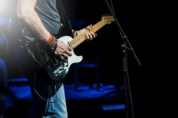 The guitarist plays the electric guitar. Guitar neck close-up on a concert of rock music in the hands of a musician.  Fingers on fretboard