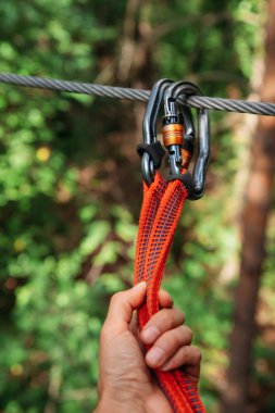 İp parkı. El, karabinaları bağlama hattına bağlıyor. Yakın plan.