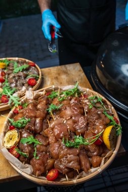 Açık havada yemek ziyafeti. Eldivenli bir şef şişte barbekü hazırlar. Eller ve et kapanıyor.