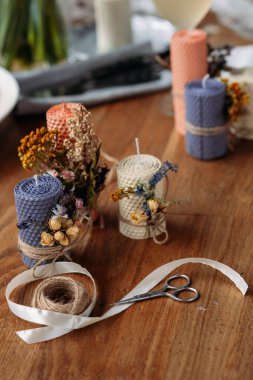 Dekoratif mumlar, makas ve sicim ahşap masada.