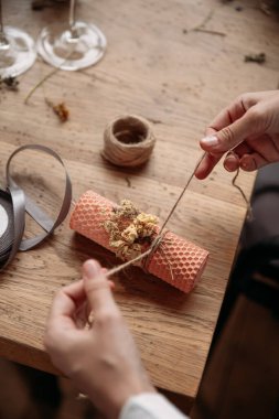 Balmumu yapma işlemi. Dekoratif mum yapan ve kurumuş çiçeklerle dekore eden bir kadın.