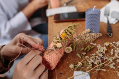 Balmumu yapma işlemi. Dekoratif mum yapan ve kurumuş çiçeklerle dekore eden bir kadın.
