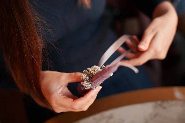 DIY wax candle making process. Woman making decorative wax candle and decorates with dried flowers, close-up of hands