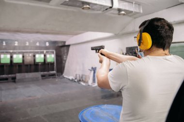 Bir salgında yaşamak. Tıbbi maskeli bir adam, bir salgının ortasında atış poligonunda silahla bir hedefi hedef alır.