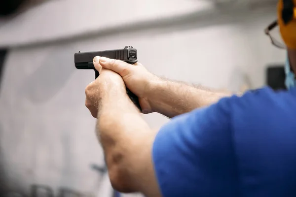 Living in a pandemic. A man in a medical mask aims at a target with a gun at a shooting range amid a pandemic