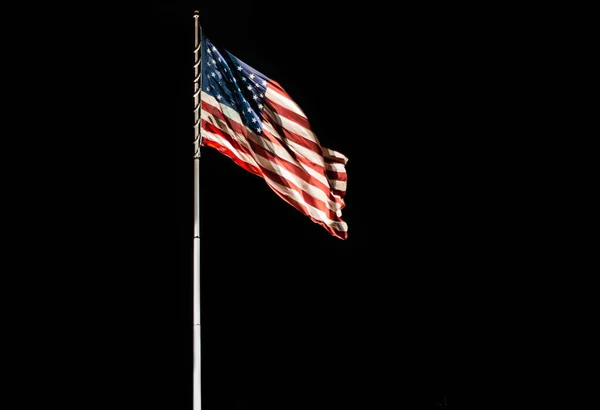Pole with waving Old Glory American flag isolated on black, copy space