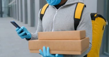 Tıbbi maskeli ve eldivenli Afro-Amerikan bir adam akıllı telefondan mesaj yolluyor, kutuları tutuyor. Teslimatçı telefonla dinleyip, harita navigatörünü kullanarak adres arıyor. Paketler teslim ediliyor.