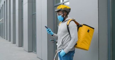 Tıbbi maskeli Afro-Amerikan kurye dışarıda bisiklet başında dikiliyor ve akıllı telefondan mesaj yolluyor. Bisikletli kurye caddede cep telefonundan kayıt yapıyor. Konsept sunma