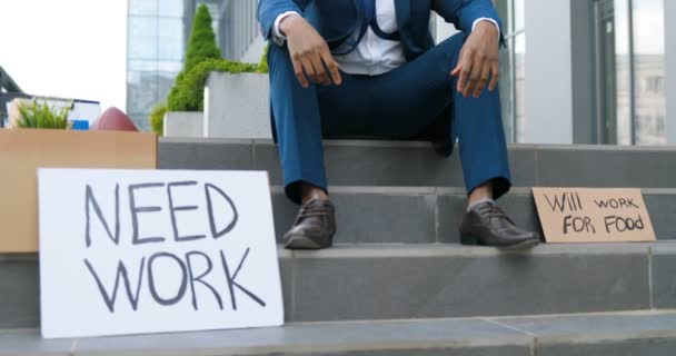 Tavoli di cartone con slogan Hai bisogno di lavoro e lavorerai per il cibo sulle scale dell'uomo africano di Amrican che siede nella disperazione. Attivista maschile contro la politica della disoccupazione . — Video Stock