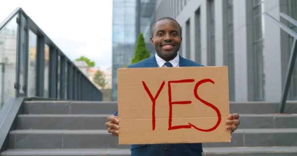 Portraitaufnahme eines afroamerikanischen männlichen Aktivisten mit Bart, der bei Demonstrationen oder Protesten ein Ja-Plakat hochhält. Einzelner Protest im Freien. Aktivismus-Konzept. Mann zeigt Tisch mit Wort Ja. — Stockvideo
