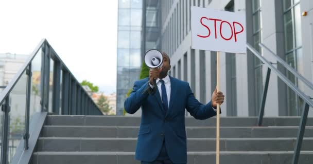 Retrato de un activista afroamericano gritando en megáfono. Hombre sosteniendo cartel Deténgase en una manifestación política o ambiental solitaria. Una sola protesta al aire libre. Concepto de activismo . — Vídeos de Stock