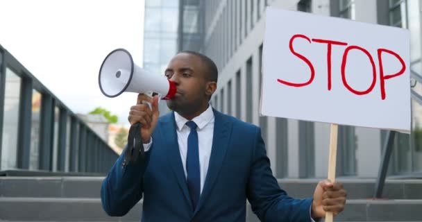 Primer plano de un activista afroamericano gritando en megáfono. Hombre sosteniendo cartel Deténgase en una manifestación política o ambiental solitaria. Una sola protesta al aire libre. Trabajo de activismo. Retrato . — Vídeos de Stock