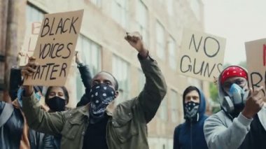 Irkçılık ve şiddete karşı posterleri olan melez gençler protestoda bağırıyor ve bağırıyorlardı. Çok ırklı erkek ve kadın protestocular sokakta slogan atıyorlar.