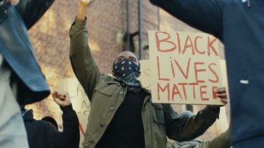Irkçılık ve şiddete karşı posterleri olan melez gençler protestoda bağırıyor ve bağırıyorlardı. Afro-Amerikan erkek protestocu posterli Siyahi hayatlar Sokakta önemli.