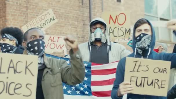 Afrikanska amerikanska och kaukasiska män i respiratorer och masker med amerikansk flagga skriker motton och deltar i demonstrationer för svarta människors mänskliga rättigheter och jämställdhet. Manifestation i USA. — Stockvideo