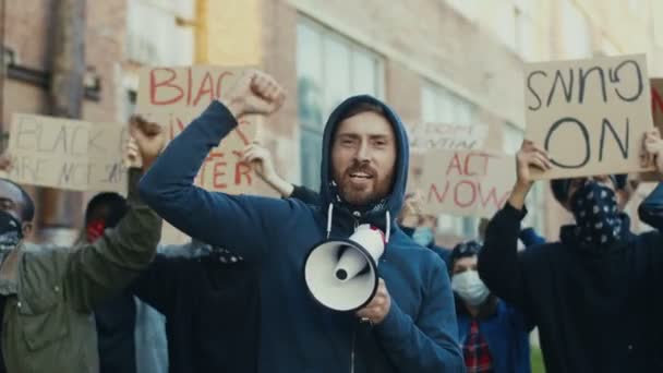 白人年轻英俊的小伙子在一群多种族的抗议者中间抗议，用扩音器大声喊着电影。在人权问题上处于领先地位的人. — 图库视频影像