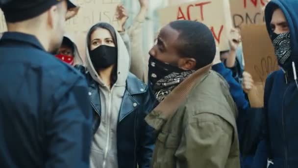 Jonge Afro-Amerikaanse man protesteert schreeuwend en schreeuwend tegen politieagent bij demonstratie voor mensenrechten. Amerikaanse demonstranten vechten en ruziën met agent bij protest tegen politiegeweld. — Stockvideo