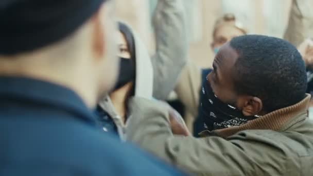 Close up of African American guy protester screaming and shouting at policeman at demonstration for human rights. USA protesters fighting and quarrelling with cop at protest against police violence. — Stock Video