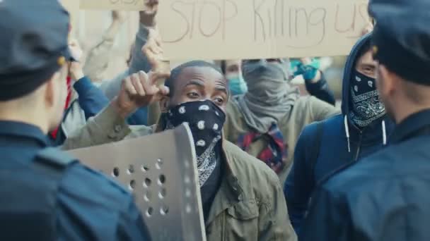 Młody Afroamerykanin protestujący i wrzeszczący na policjantów podczas demonstracji o prawa człowieka. Protestujący USA walczą i kłócą się z glinami w proteście przeciwko przemocy policyjnej. — Wideo stockowe