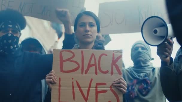 Молодая белая красивая женщина, стоящая в кричащей толпе с плакатом "Жизнь чернокожих важна". США протестуют против расизма и полицейского насилия. Девушка на демонстрации за равенство . — стоковое видео