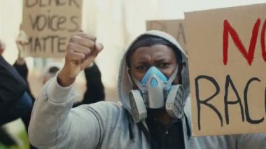 Irkçılığı ve bağıran sloganları protesto eden kapüşonlu ve gaz maskeli genç Afrikalı Amerikalılara yakın durun. Açık havada. Solunum cihazındaki adam polise karşı tezahürat yapıyor..