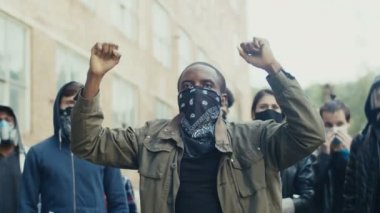 Afro-Amerikalı genç yakışıklı adam çok ırklı ve bağıran sloganların ortasında protesto yapıyor. İnsan hakları tezahüratında başı çeken adam.