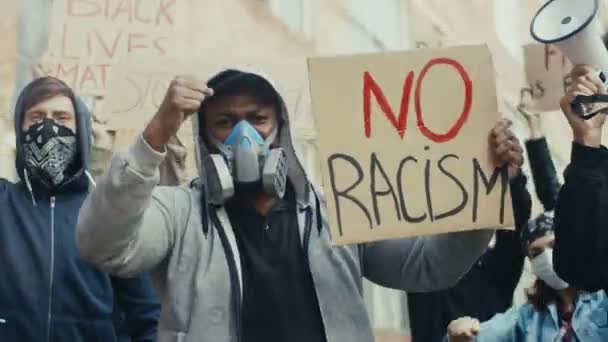 Blandade raser unga män i gasmasker som innehar affischer mot rasism på gatan. Multietniska killar i respiratorer på manifestation i USA mot polisbrutalitet. Stadsstrejk för frihet. — Stockvideo